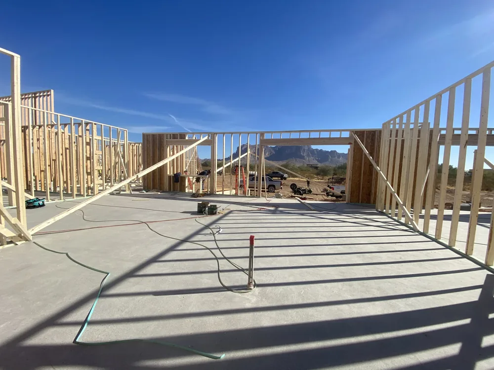 New wall framing and concrete slab under an open blue sky
